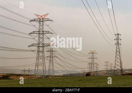Electricity pylons at sunset, power transmission lines Stock Photo