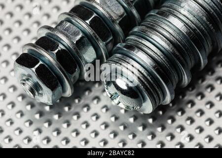 cool blue toned macro of small bolts with nuts and washers on an industrial steel surface.  Strong Contrast Stock Photo