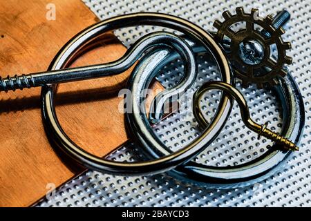 An oxidized and used copper and Stainless steel surface with several stainless steel rings and screw hooks, a brass screw hool and a brass gear.  Indu Stock Photo