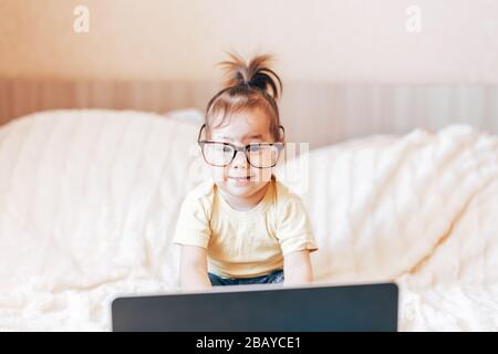 Little happy funny black-haired girl using laptop Stock Photo