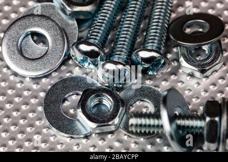 cool blue toned macro of small bolts with nuts and washers on an industrial steel surface.  Strong Contrast throughout the image. Stock Photo