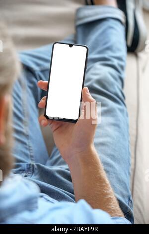 Young man reading social media news using smart phone mock up screen. Vertical Stock Photo