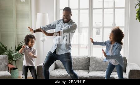 Young african ethnicity father teaches little kids to dance Stock Photo