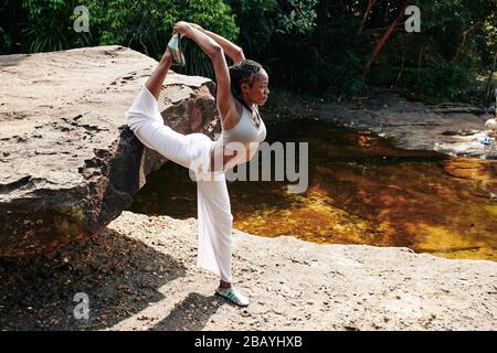 Serious young yogi doing stretching exercise when enjoying getaway Stock Photo