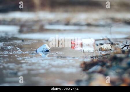 Abandoned empty pink plastic bottle and blue can garbage at the river bank conservancy pollution Stock Photo