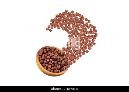 Chocolate balls for breakfast beautifully falling out of wooden bowl. Curved shape. Isolated on white background. Stock Photo