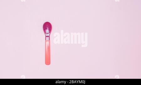 pink and purple plactic color Baby spoon on pink background flatlay Stock Photo