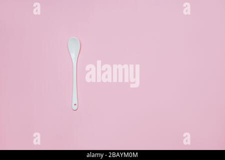 Ceramic white spoon on a pink background copy space Stock Photo