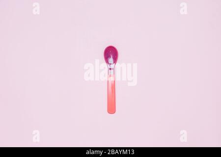 pink and purple plactic color Baby spoon on pink background flatlay Stock Photo