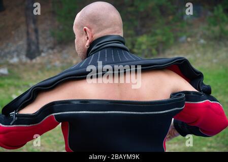 Diver puts on a wetsuit. Close up of diver in wet suit prepares for the dive, checks and puts on the equipment Stock Photo