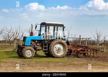 Teplik, Ukraine 28.03.2020 MTZ Belarus with cultivator. A tractor ready for field work stands near the garden on the field. Stock Photo