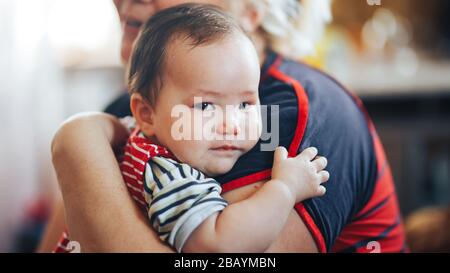 Grandmother cradling crying infant baby girl looking at camera Stock Photo