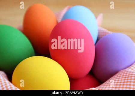Closeup Multi-colored Easter Eggs in a Basket on Wooden Background Stock Photo