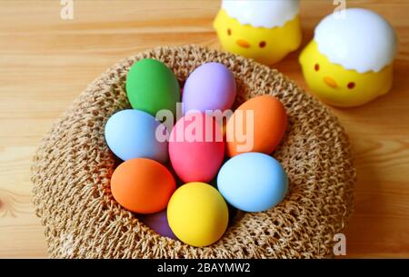 Closeup Multi-colored Easter Eggs in a Basket with Blurry Two Adorable Chicks in Background Stock Photo