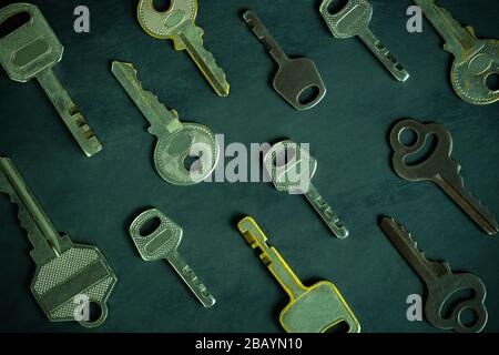 Close up much different variety of vintage keys orderly on black wooden table in darkness background. The idea for the key to solving business problem Stock Photo