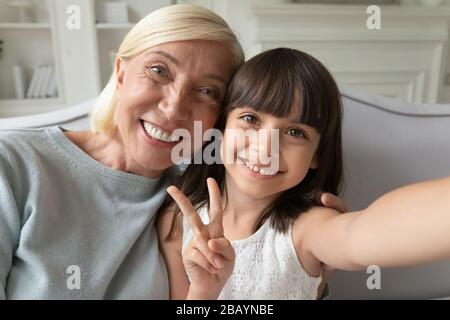 Little granddaughter and grandmother take selfie together Stock Photo