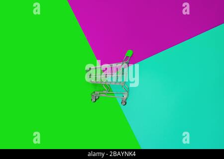 Top view of empty shopping trolley on colorful bright background. Concept of shopping and consumerism. Minimal flat lay Stock Photo
