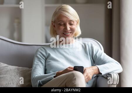 Smiling senior woman using smartphone at home Stock Photo