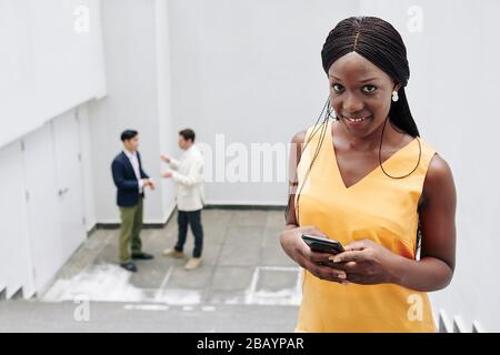 Attractive smiling young Black businesswoman checking notifications on her smartphone Stock Photo