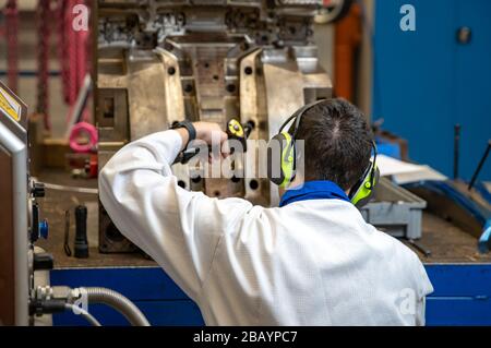the engineer performs freezing of the casting using a special machine. maintenance of metal molds for plastic castings in the factory Stock Photo