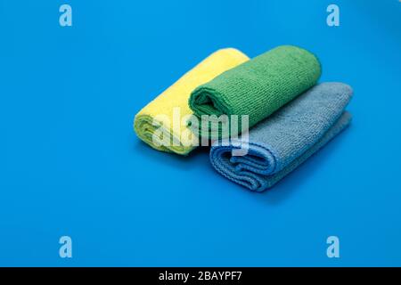 Colorful, dry microfiber cloths for different surfaces cleaning in kitchen, bathroom and other rooms, on blue background. Empty place for text or logo Stock Photo