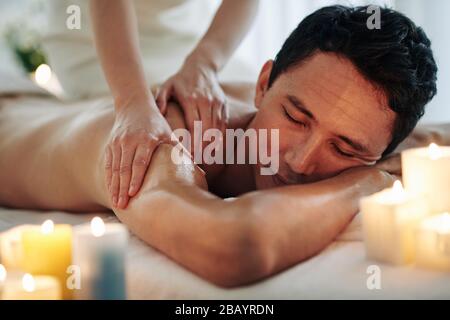 Handsome middle-aged man enjoying relaxing spa massage with oils Stock Photo