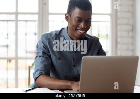 African office employee sitting at workplace typing on laptop Stock Photo