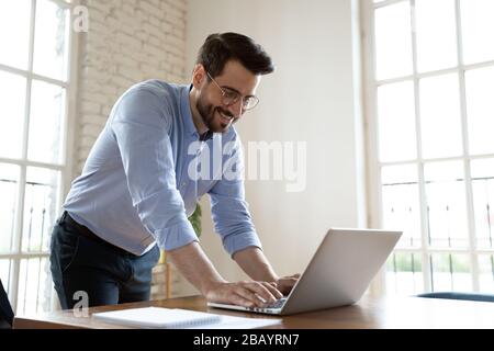 Businessman leaning over table in boardroom responds on business email Stock Photo