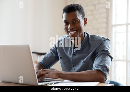 Smiling African businessman working sitting at workplace smile for camera Stock Photo