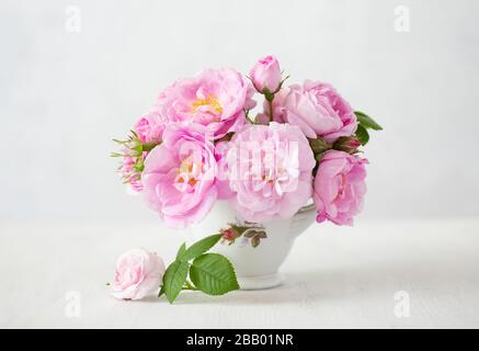 Small light pink bouquet of Roses in porcelain vase against of pale grey background.  Shallow depth of field. Selective focus. Stock Photo