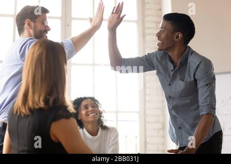 African and Caucasian buddies giving high five greeting each other Stock Photo