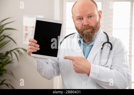 Serious adult male doctor showing a digital image or report on a tablet Stock Photo