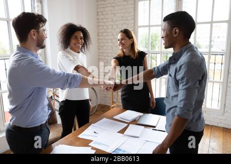 Diverse associates putting fists together showing amity and support Stock Photo