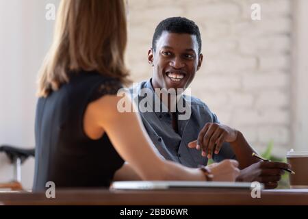 Multi-ethnic smiling teammates working together sitting at desk Stock Photo