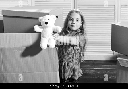 Only true friend. Girl child play with toy near boxes. Move out concept. Prepare for moving. Moving out. Moving routine. Packaging things. Stressful situation. Divorce and separation. Family problem. Stock Photo