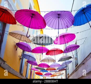 Multi-colored umbrellas in the sky above the street Stock Photo