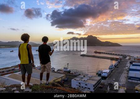 Young Men Admiring the Sunset on Monte Cara and Porto Grande Bay seen from Fortim del Rei, Mindelo, Sao Vicente, Cape Verde Islands, Africa.