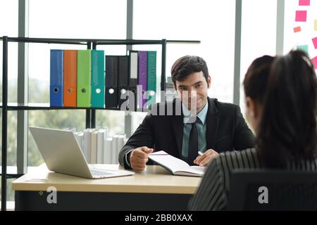 Young employers in black suits are evaluating job applicants by asking marketing strategy questions. Stock Photo