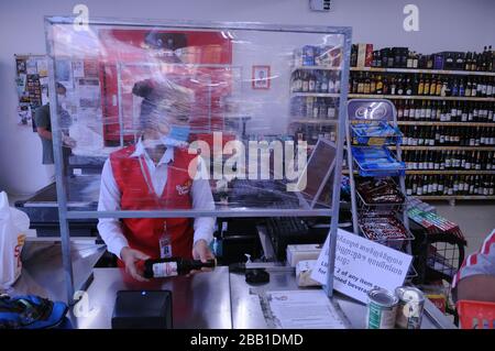 A supermarket cashier wears a face mask behind a homemade plastic shield during the coronavirus pandemic. Phnom Penh, Cambodia. © Kraig Lieb Stock Photo