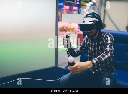 Bearded man wearing virtual reality goggles in modern coworking studio. Smartphone using with VR headset. Horizontal, blurred Stock Photo