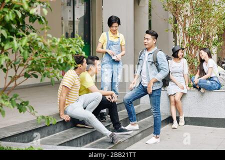 Students standing at entrance of college or university during break, discussing homework and news Stock Photo