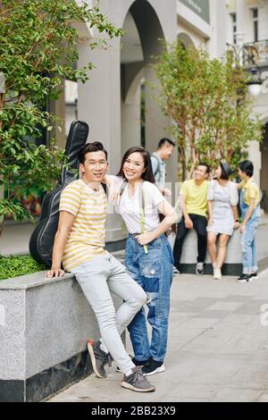 Cheerful Vietnamese college students standing at campus entrance and looking at camera Stock Photo