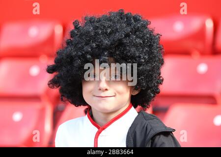 A young Manchester United fan wears a Marouane Fellaini wig in the stands at Old Trafford Stock Photo