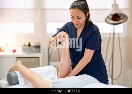 Medical massage at the leg in a physiotherapy center. Stock Photo