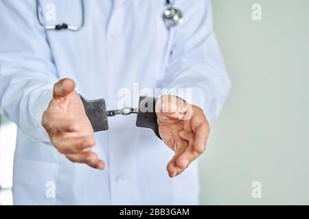 Close-up Of Arrested Doctor's Hand With Handcuffs Stock Photo