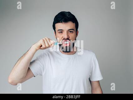 Young man isolated over background. Health and beauty concept - guy with toothbrush healthcare and sile treatment. Cleaning mouth Stock Photo