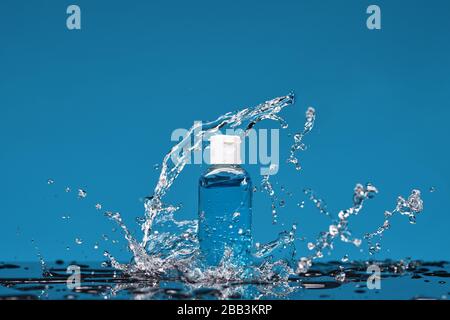 Bottle of antiseptic gel in splashes of water. Concept of washing hand, hygiene and prevention measures from the Covid-19 Corona virus. Stock Photo