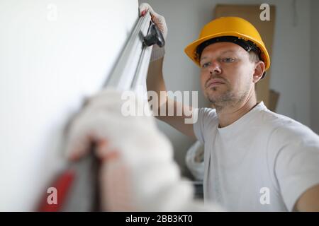 Builder helmet measures wall level with building Stock Photo