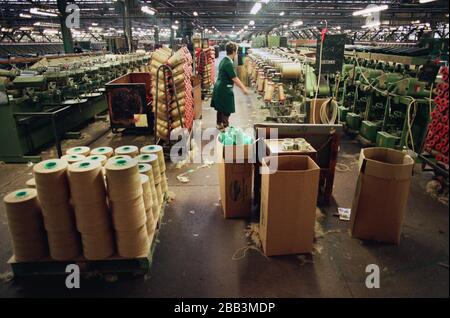 A worker supervising a machine at Tay Spinners mill in Dundee, Scotland. This factory was the last jute spinning mill in Europe when it closed for the final time in 1998. The city of Dundee had been famous throughout history for the three 'Js' - jute, jam and journalism. Stock Photo