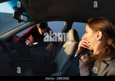 A man attacked a defenseless woman in a parking lot, he is trying to take her purse from her. Stock Photo